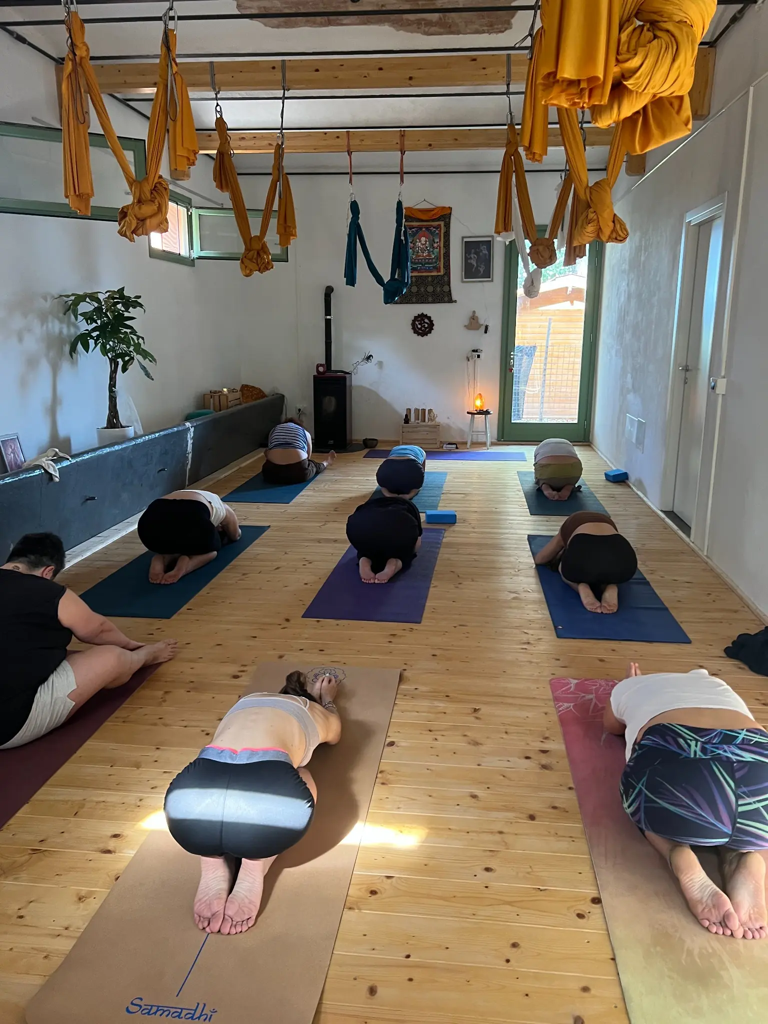 Una lezione nella sala di Simila Yoga a Palaia, con spazio per il lavoro a terra e con le amache.